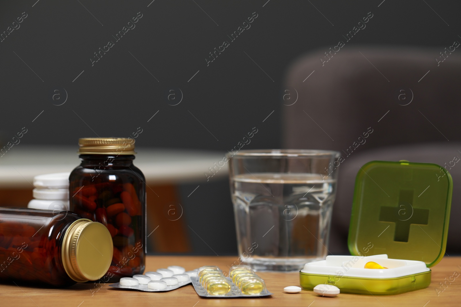 Photo of Plastic pill box and different medicaments on wooden table indoors, space for text