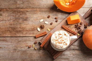 Photo of Flat lay composition with cup of tasty pumpkin spice latte and space for text on wooden background