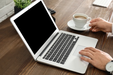 Photo of Man using laptop at table, closeup. Space for design