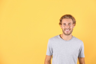 Photo of Handsome young man laughing on color background. Space for text