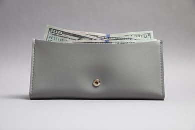 Photo of Stylish leather purse with dollar banknotes on light grey background