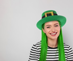 Image of St. Patrick's day party. Pretty woman with green hair and leprechaun hat on light grey background. Space for text