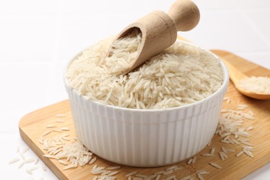 Photo of Raw basmati rice in bowl and scoop on white table