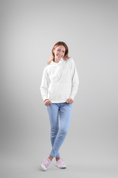 Photo of Full length portrait of woman in hoodie sweater on light background. Space for design