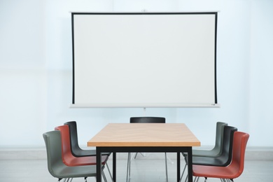 Photo of Conference room interior with wooden table and video projection screen