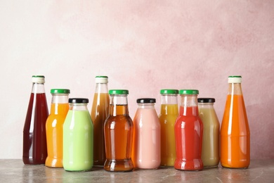 Photo of Bottles with different drinks on table against color background
