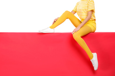 Photo of Woman wearing yellow tights sitting on color background, closeup. Space for text