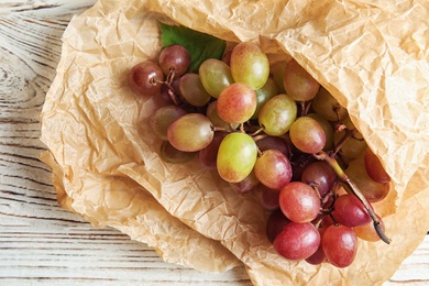 Photo of Fresh ripe juicy grapes and paper on table, top view