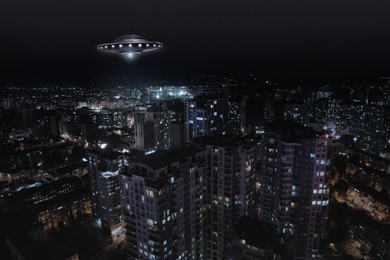 Image of Alien spaceship flying over city at night. UFO, extraterrestrial visitors