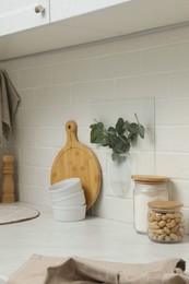 Photo of Silicone vase with eucalyptus branches on wall over countertop in kitchen