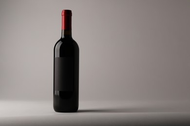 Photo of Bottle of tasty red wine on light background, space for text