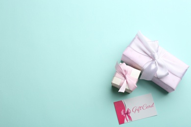 Photo of Gift card and presents on light blue background, flat lay. Space for text