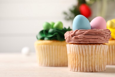 Photo of Tasty decorated Easter cupcakes on wooden table, closeup. Space for text
