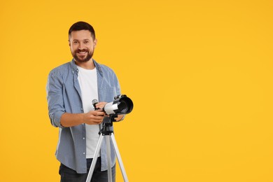 Photo of Happy astronomer with telescope on orange background. Space for text