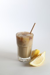 Photo of Iced coffee with milk in glass and cut lemon on white background
