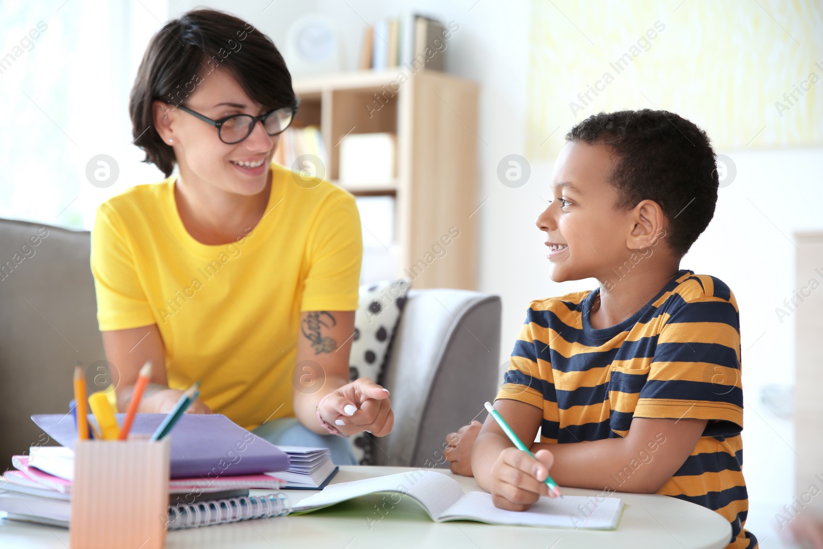 Photo of Young woman helping her child with homework at home. Elementary school
