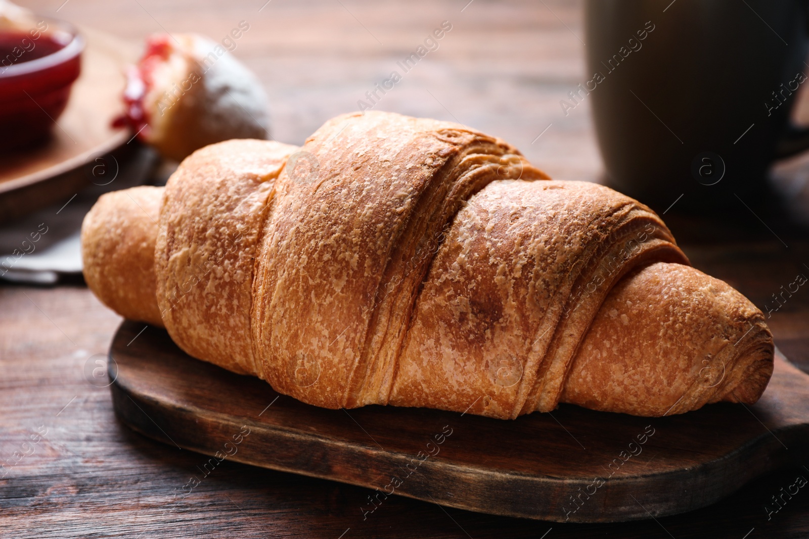 Photo of Tasty fresh croissant on wooden table, closeup