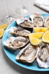 Photo of Fresh oysters with lemon on grey table, closeup