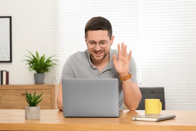 Photo of Man having video chat via laptop at wooden table at home