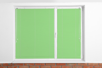 Image of Window with closed green blinds in room