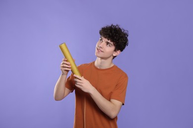 Photo of Teenage boy with party popper on violet background