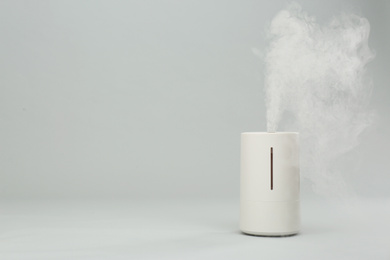 Photo of Modern air humidifier on light grey background. Space for text