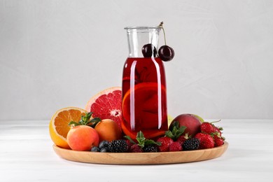 Photo of Delicious refreshing sangria, fruits and berries on white wooden table