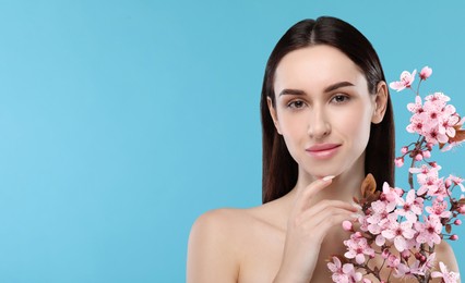 Image of Beautiful woman with smooth skin and flowers on light blue background. Space for text