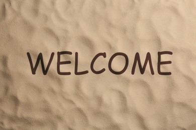 Image of Word WELCOME and dry beach sand, top view