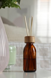 Photo of Aromatic reed air freshener on white table in room