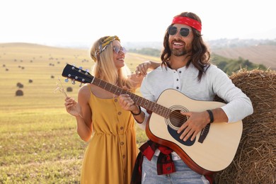 Photo of Beautiful hippie woman listening to her friend playing guitar in field