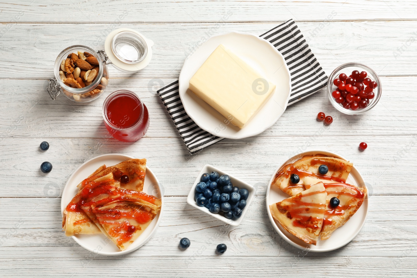 Photo of Flat lay composition with thin pancakes and toppings on table