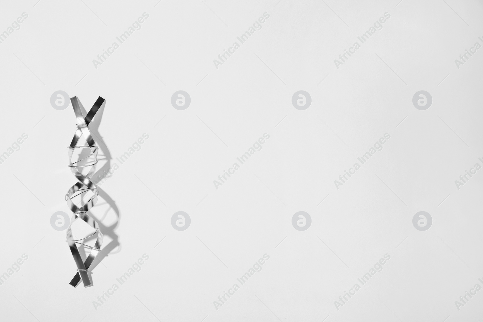 Photo of DNA molecular chain model made of metal on white background, top view. Space for text