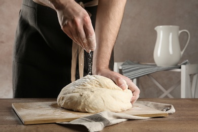 Photo of Male baker preparing bread dough at table, closeup