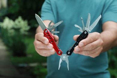 Photo of Man holding compact portable multitool outdoors, closeup