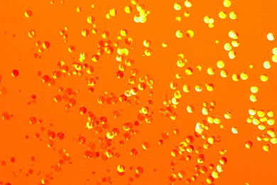 Photo of Shiny bright glitter on orange background, flat lay