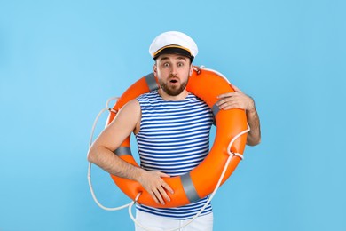 Photo of Surprised sailor with ring buoy on light blue background