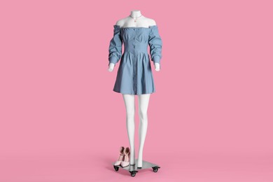 Photo of Female mannequin with shoes and necklace dressed in light blue dress on pink background. Stylish outfit