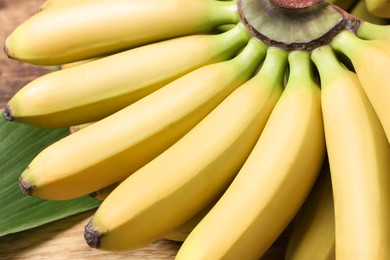 Photo of Bunch of ripe baby bananas on wooden table, closeup