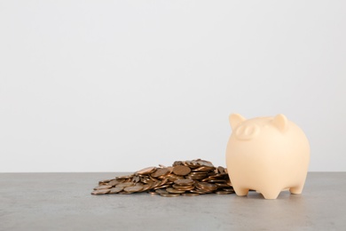 Photo of Piggy bank and coins on table against white background. Space for text