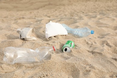 Photo of Different garbage scattered on sand. Recycling problem