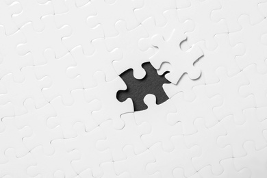 Photo of Blank white puzzle with separated piece on black background, top view
