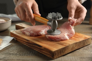 Photo of Woman cooking schnitzel at wooden table, closeup
