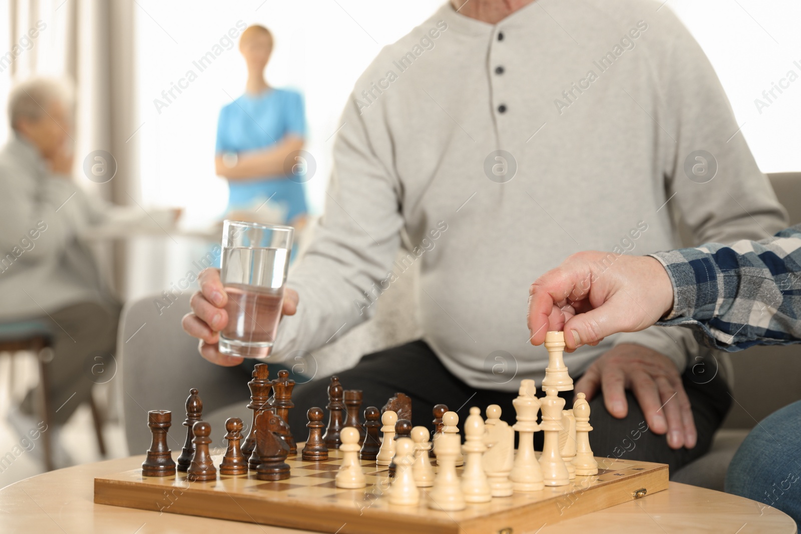 Photo of Elderly men playing chess at nursing home, closeup. Assisting senior people