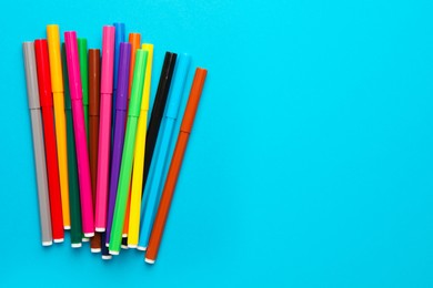 Photo of Many bright markers on light blue background, flat lay. Space for text