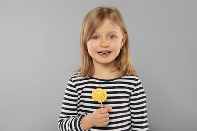 Photo of Portrait of happy girl with lollipop on light grey background