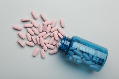 Photo of Vitamin pills and bottle on grey background, top view