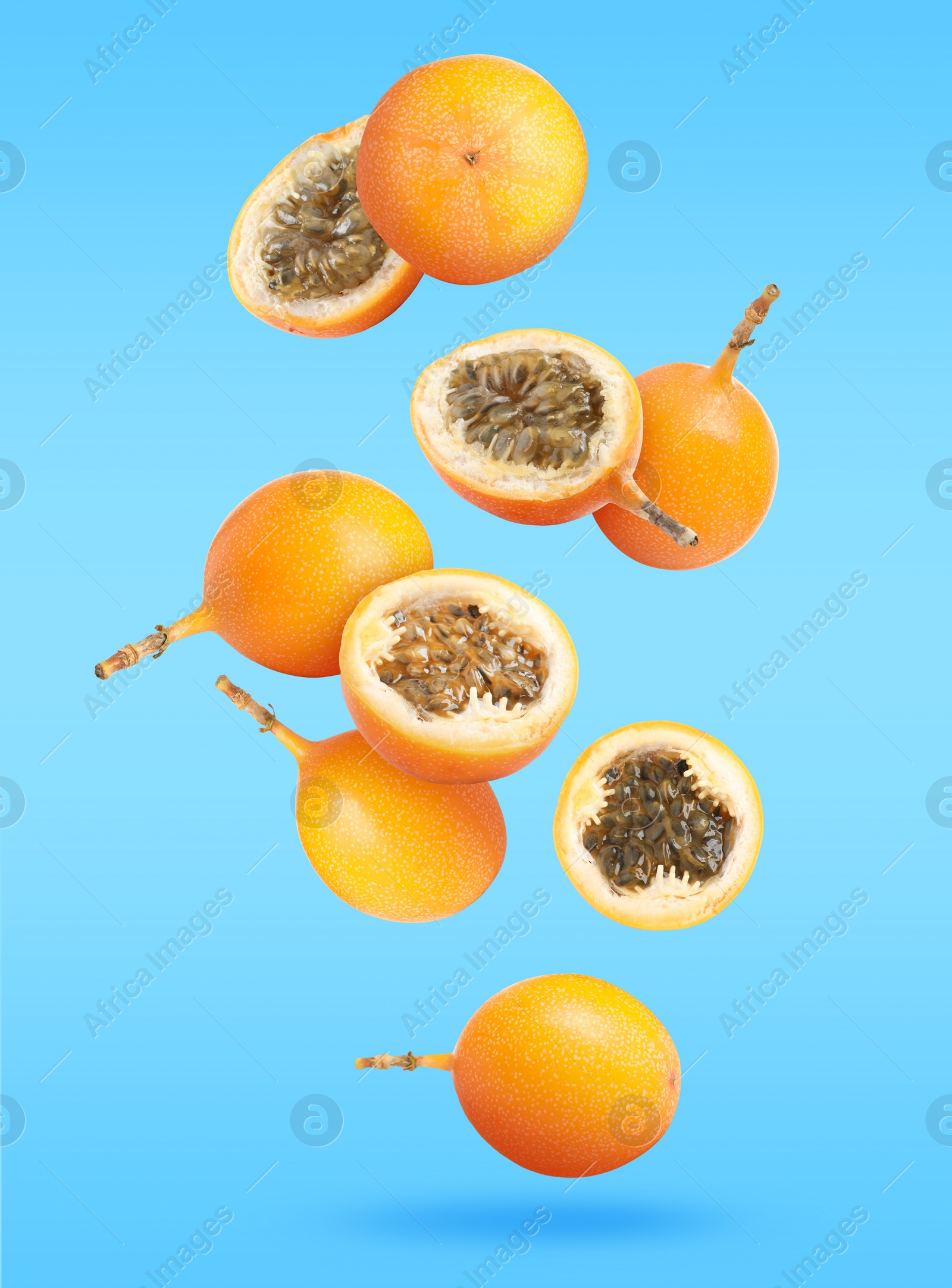 Image of Delicious ripe granadillas falling on light blue background