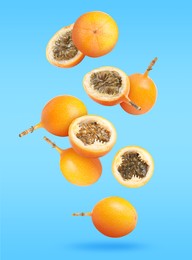 Delicious ripe granadillas falling on light blue background