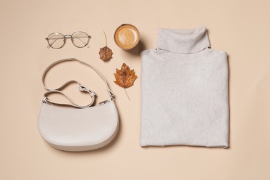 Photo of Autumn sweater, bag and eyeglasses on beige background, flat lay